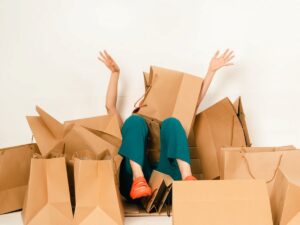 Happy young woman surrounded by shopping bags on the floor, lifting her foot.