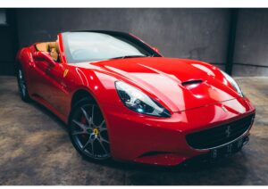 High-end red automobile parked on city street. The image represents one of the common Things Rich People Buy, as luxury cars are often associated with wealth and status.