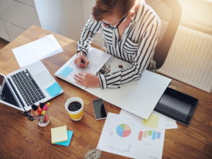 Image of a woman sitting at her desk with her laptop, explaining how to improve credit score by disputing hard inquiries online and requesting to remove hard inquiries.